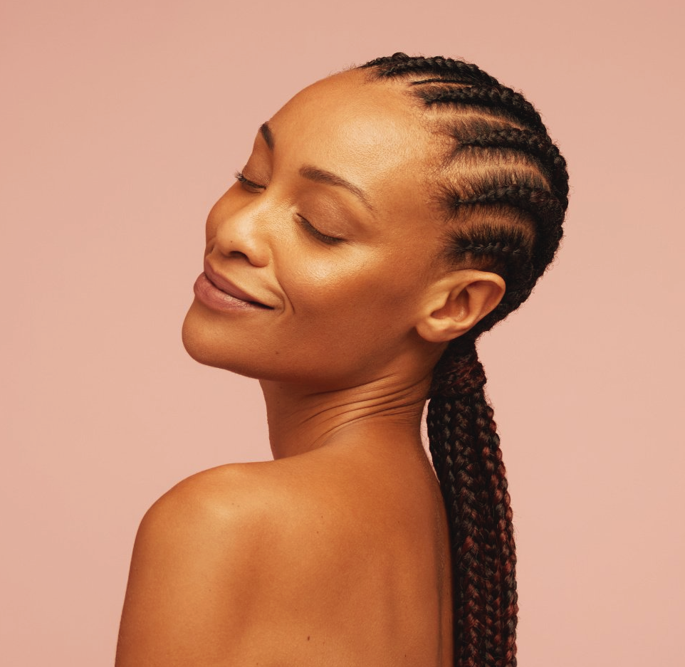 Uma mulher com tranças está sorrindo com os olhos fechados