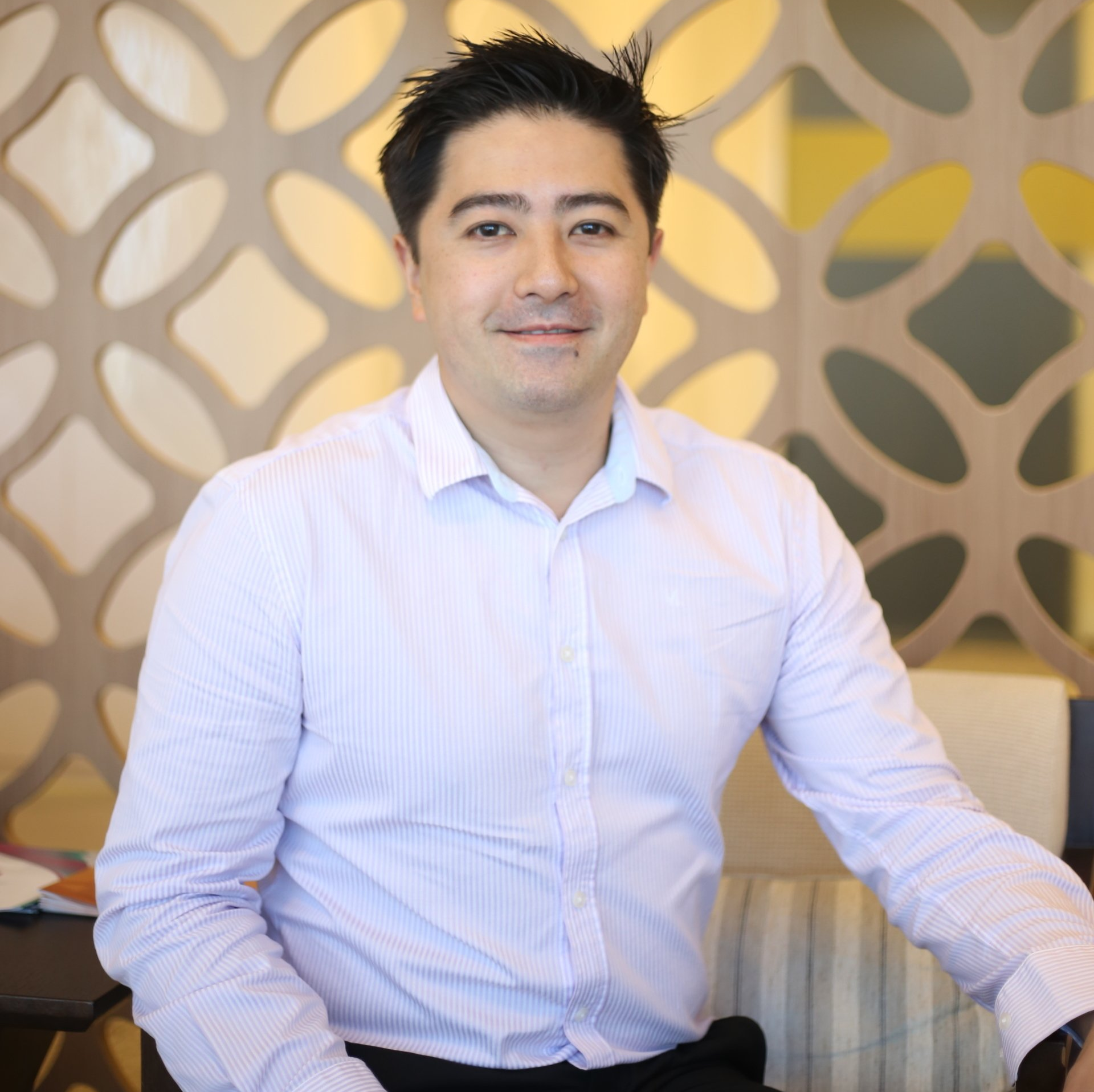 Um homem de camisa branca está sentado em uma cadeira