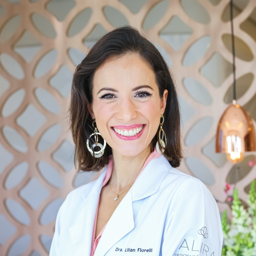 Uma mulher de jaleco sorri para a câmera