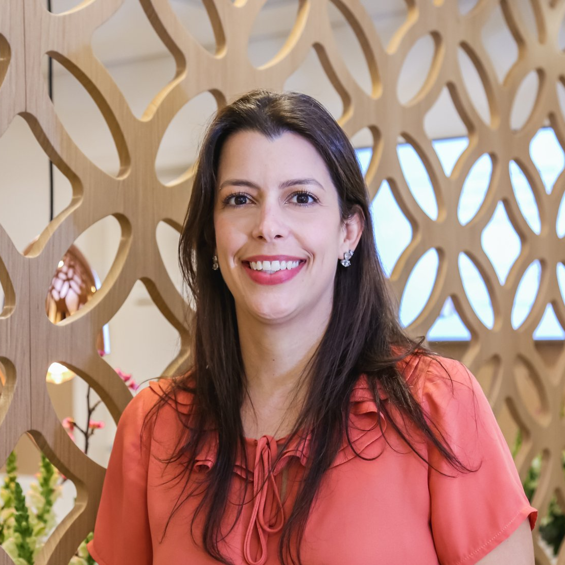 Uma mulher de camisa vermelha está sorrindo em frente a uma parede de madeira.