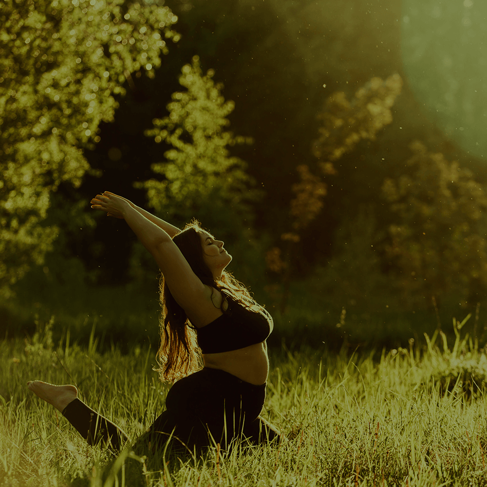 Uma mulher está ajoelhada em um campo com os braços estendidos.