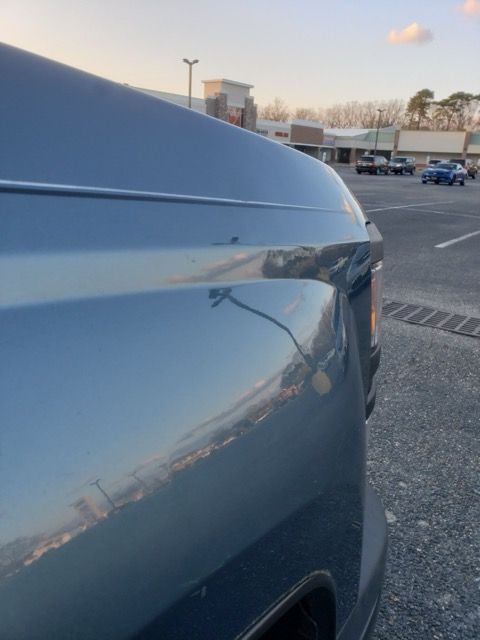 A blue truck is parked in a parking lot