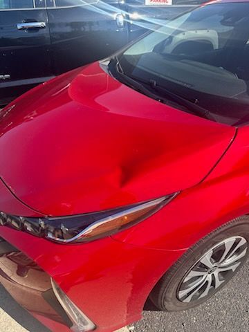 A red car is parked in a parking lot next to a black car.