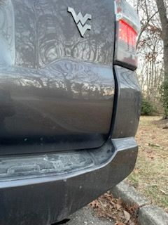 A close up of the back end of a car parked on the side of the road.