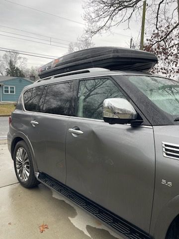 A gray suv with a roof rack on top of it is parked in a driveway.