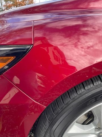 A close up of a red car 's fender and tire.