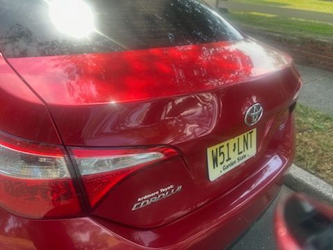 A red toyota corolla is parked in a parking lot.