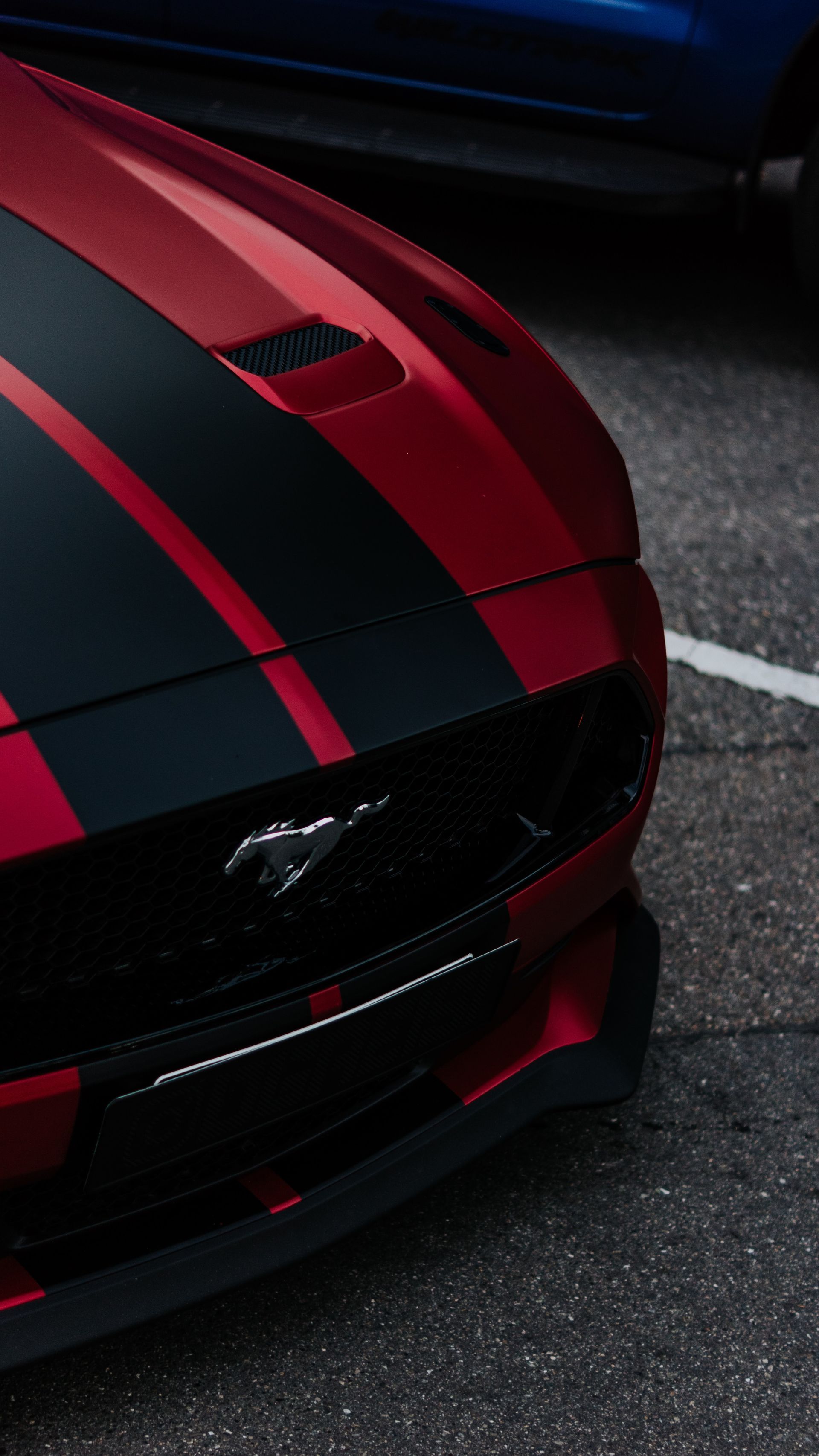 A red Mustang with black stripes on the hood.