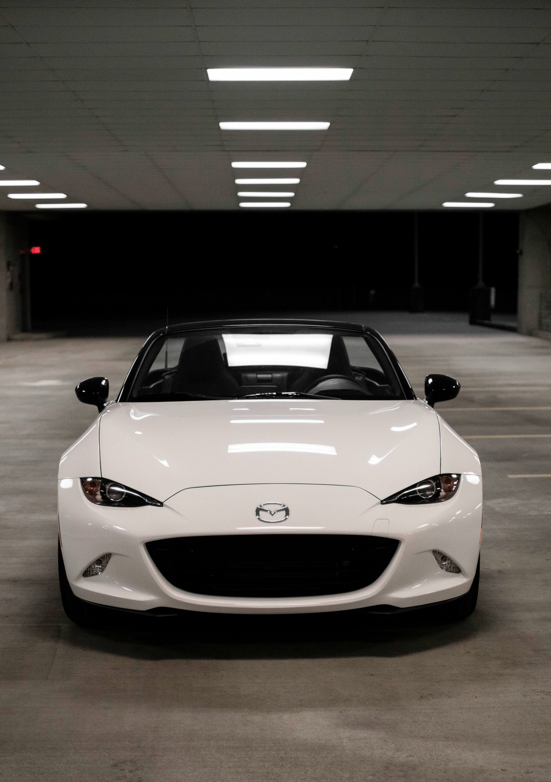 Front view of a white Mazda MX-5 in a parking lot.