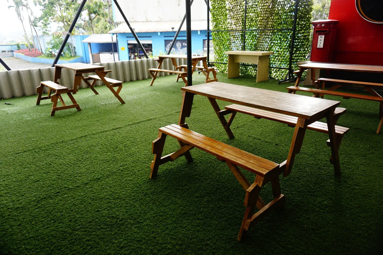 Outdoor dining area with wooden picnic tables and benches on green turf.