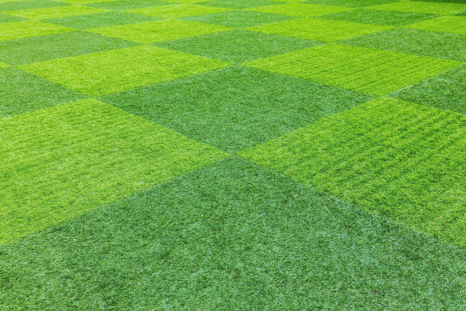 Green checkerboard pattern of two shades of artificial grass.