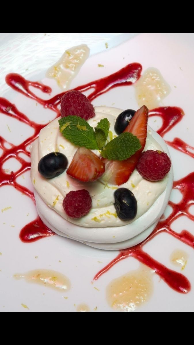 Un dessert avec des fraises, des framboises et des myrtilles sur une assiette blanche
