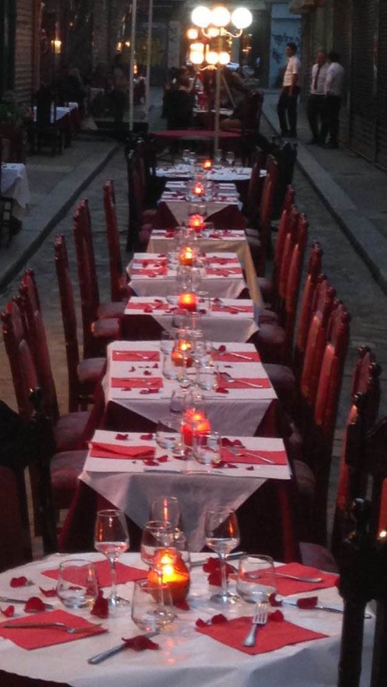 Une longue rangée de tables avec des serviettes rouges et des bougies