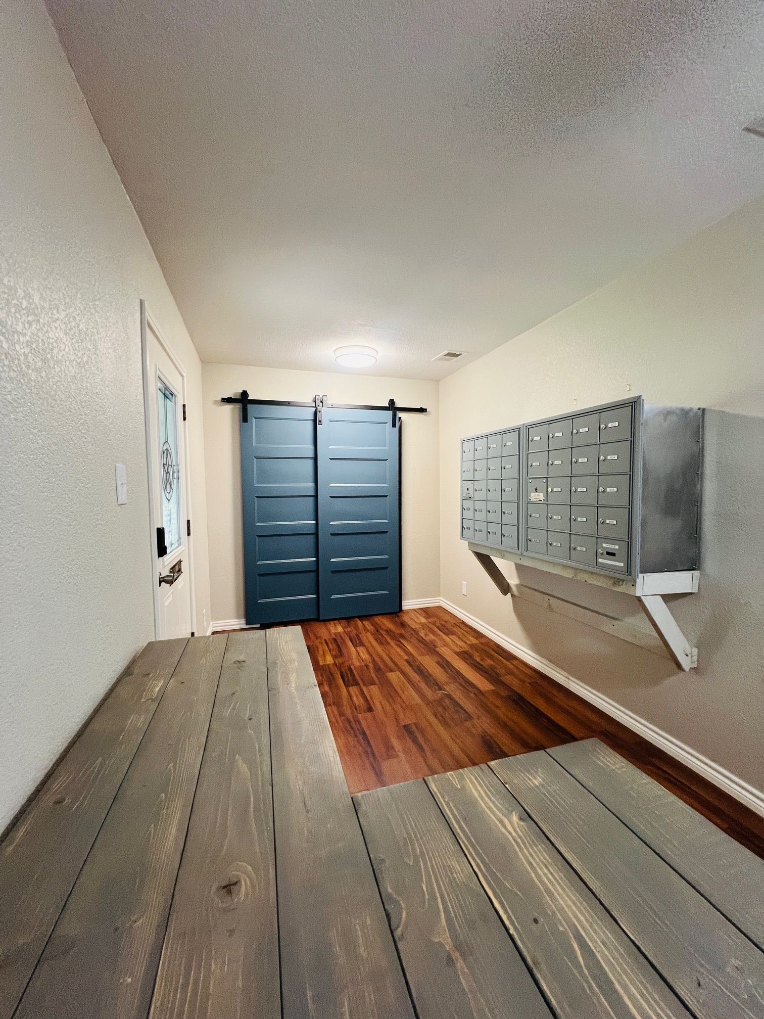 A hallway with sliding barn doors and mailboxes on the wall.