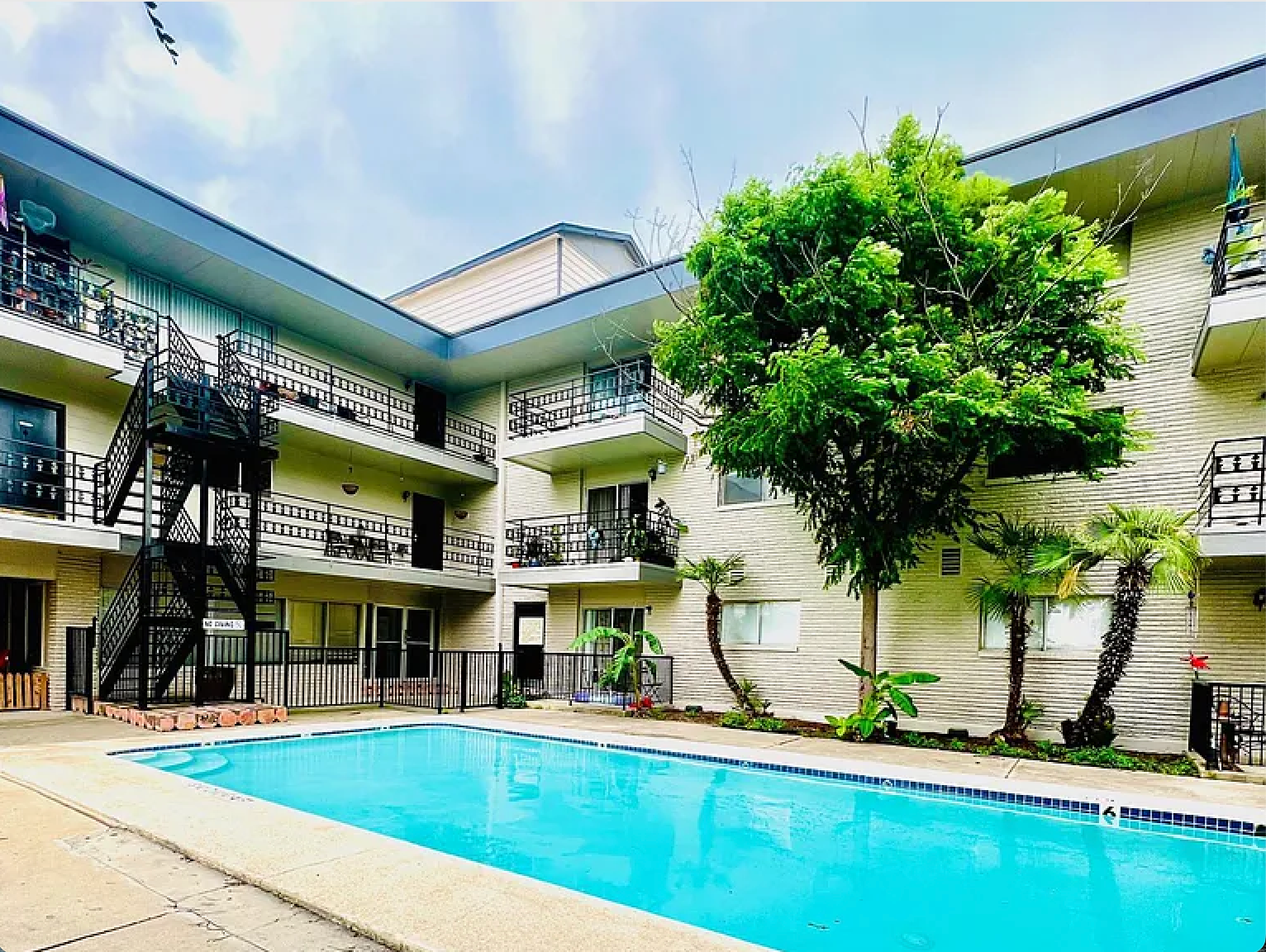 A large apartment building with a swimming pool in front of it.