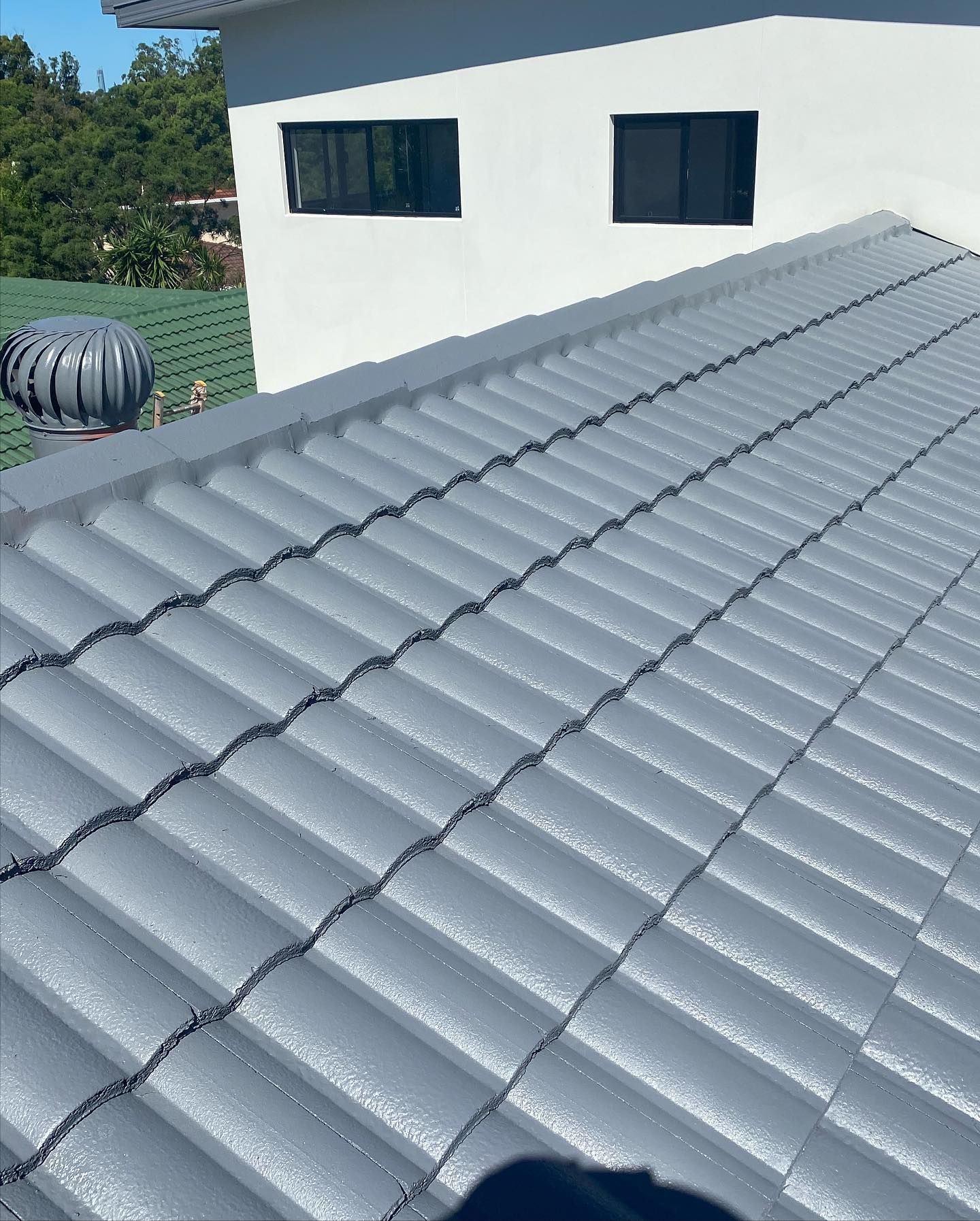 Gray Tile Roof of a White Building With Black Framed Windows — SEQ Roofing & Painting in Labrador, QLD