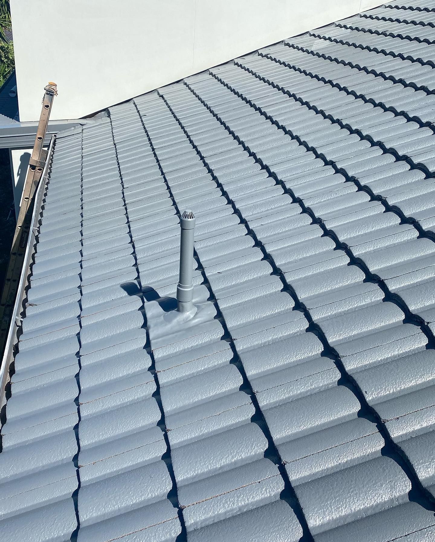 Gray Tiled Roof With a Vent Pipe Extending Upwards — SEQ Roofing & Painting in Hope Island, QLD