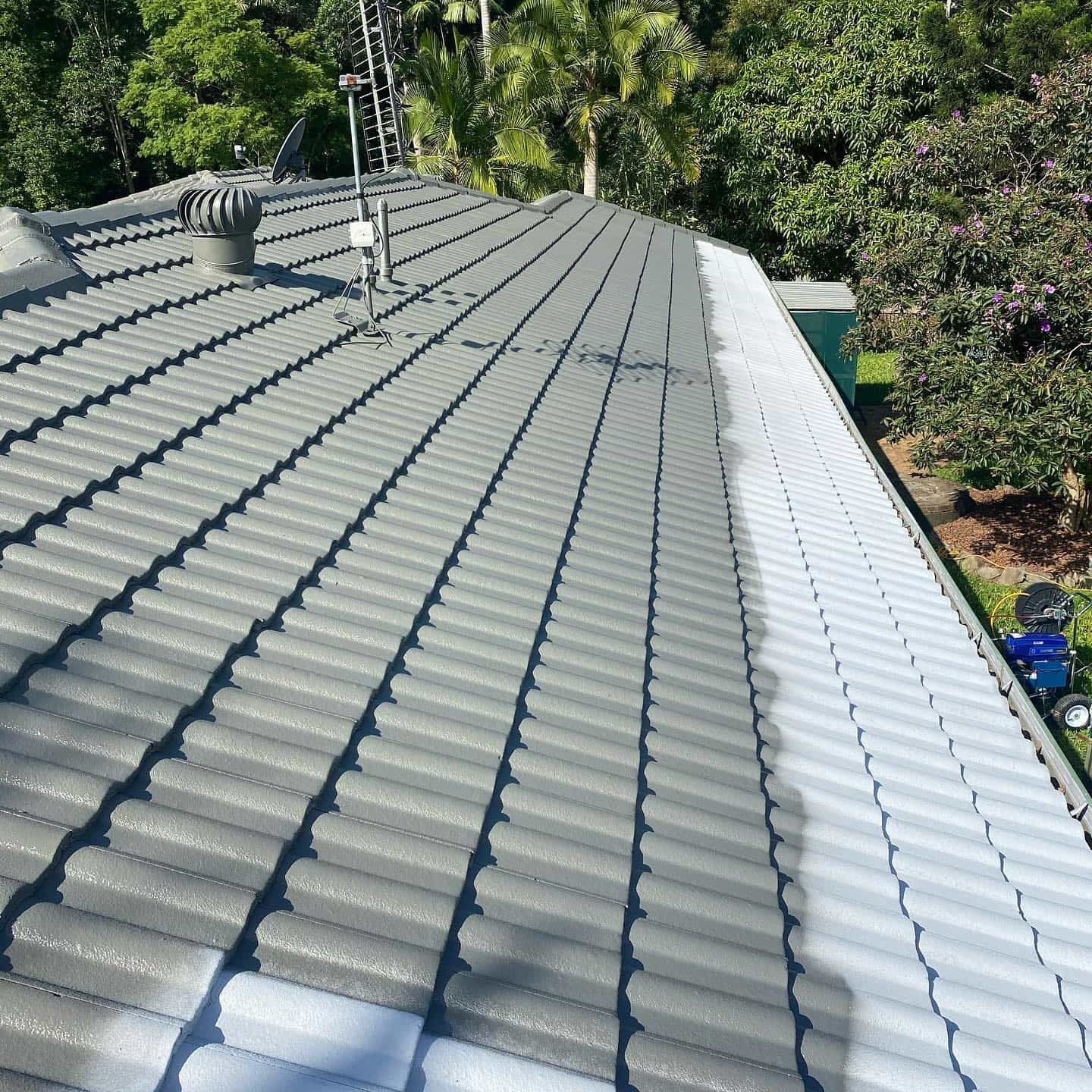 Gray tiled roof, half painted, showing the process of a roof restoration with trees in the background. — SEQ Roof Repaints In Bonogin, QLD