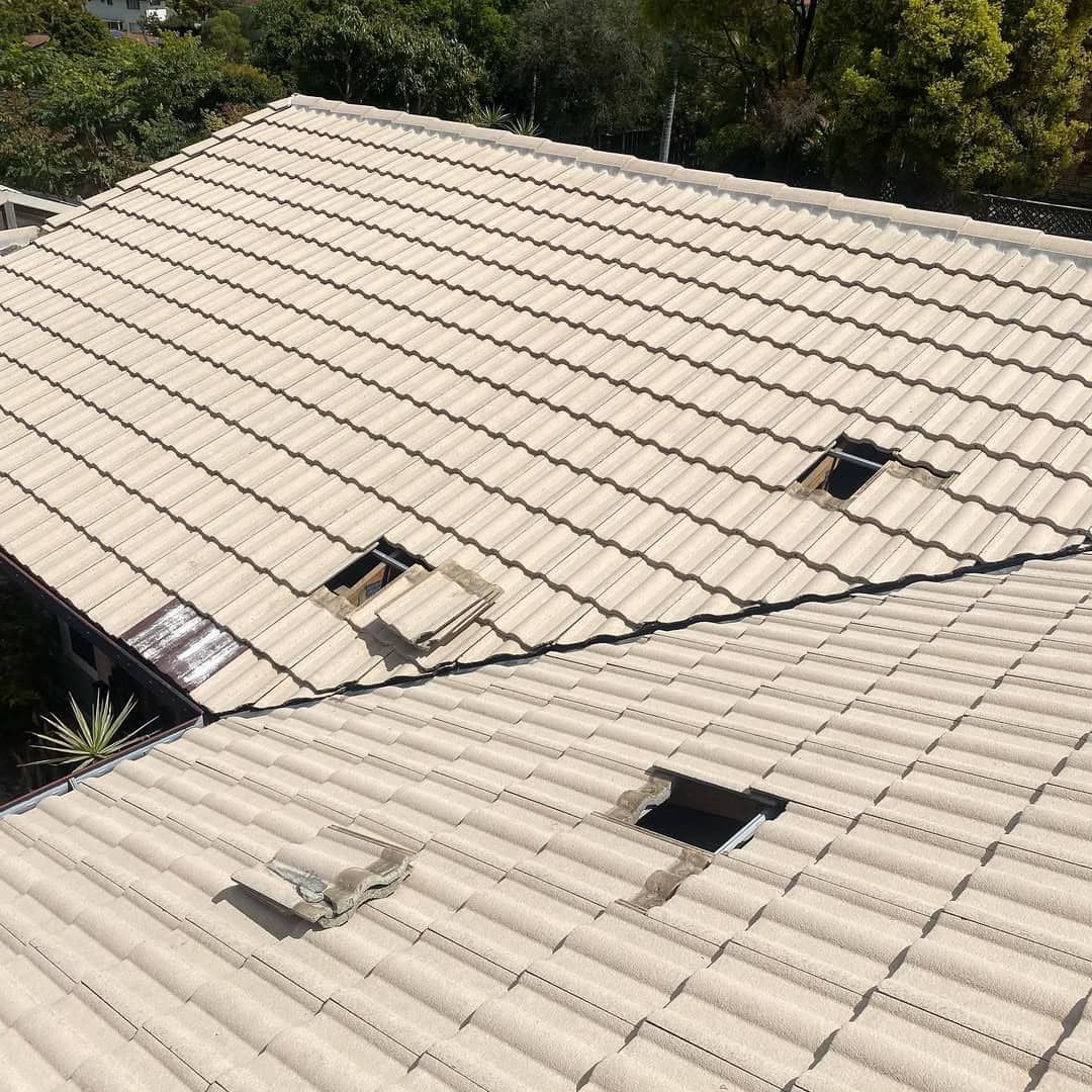 Beige tile roof with several holes and surrounding trees. — SEQ Roof Repaints In Logan, QLD