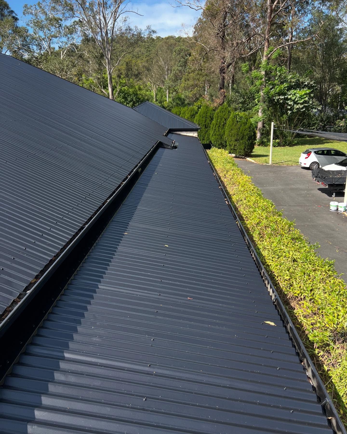 Black Corrugated Metal Roof With Gutter, Foliage, and Car in the Background — SEQ Roofing & Painting in Isle of Capri, QLD