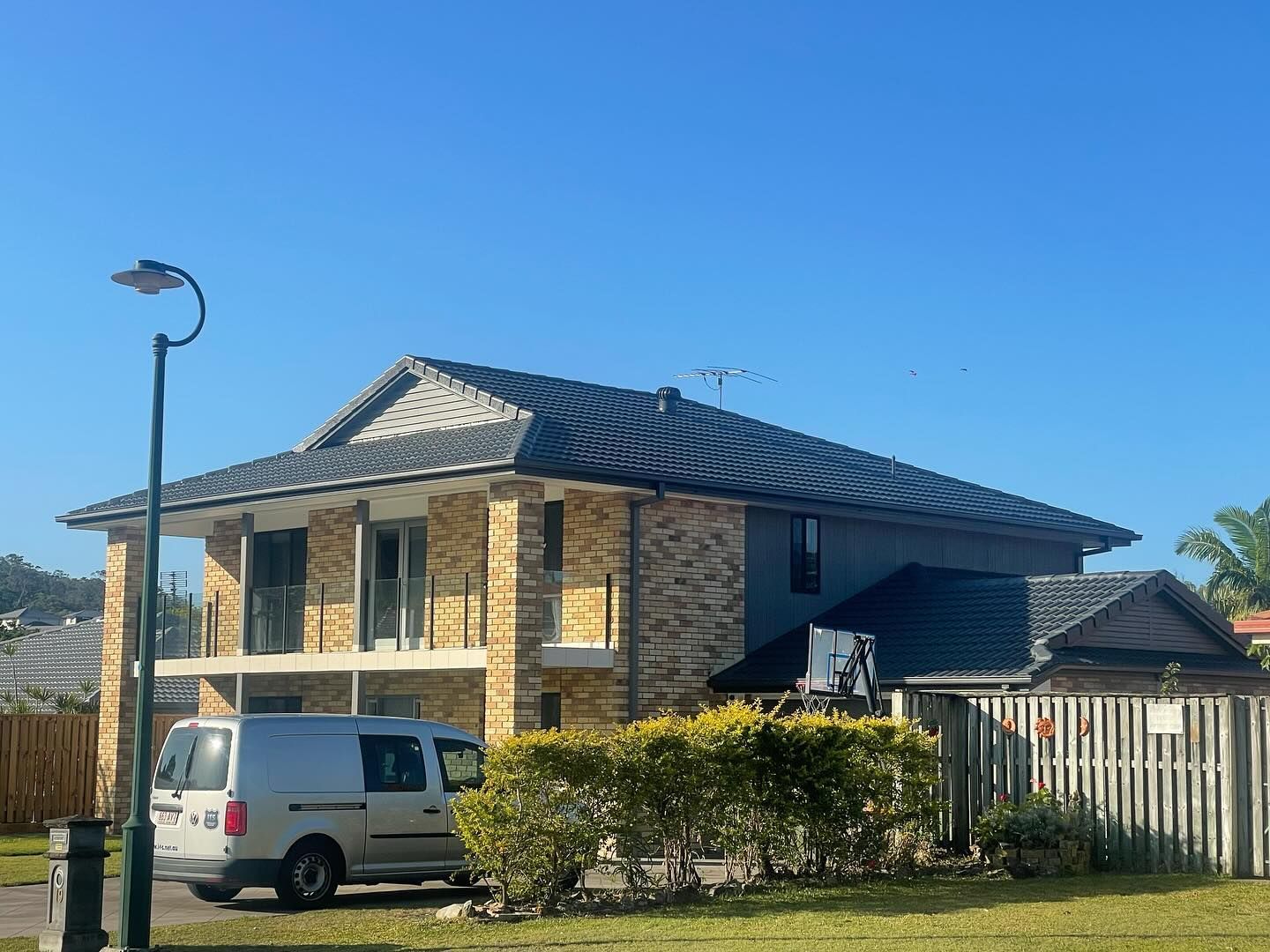 Two-story House With Gray Roof and Brick Facade; Parked Silver Van — SEQ Roofing & Painting in Mermaid Waters, QLD