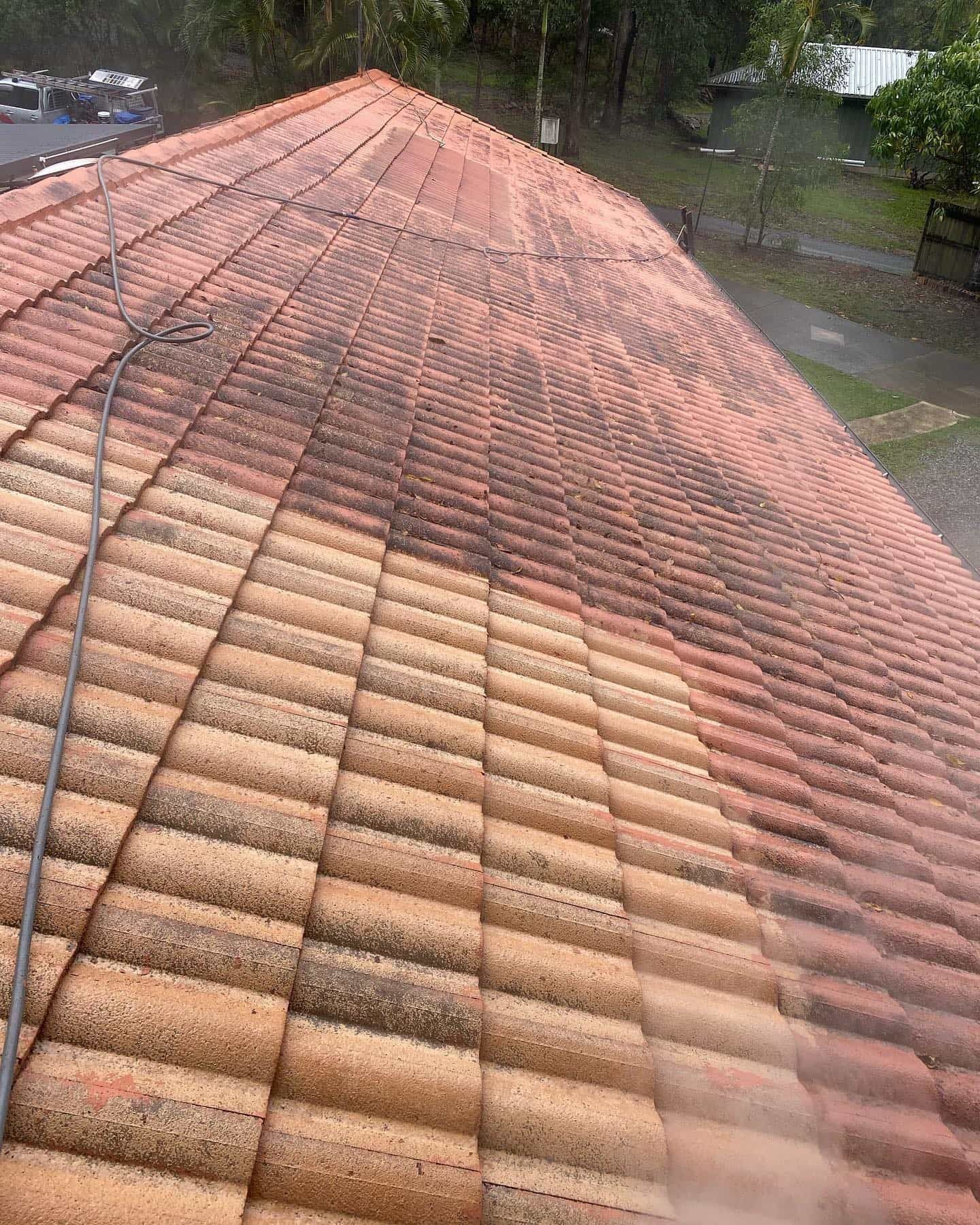 A roof being cleaned with a pressure washer, showing a clear contrast between clean and dirty areas. — SEQ Roof Repaints In Bonogin, QLD