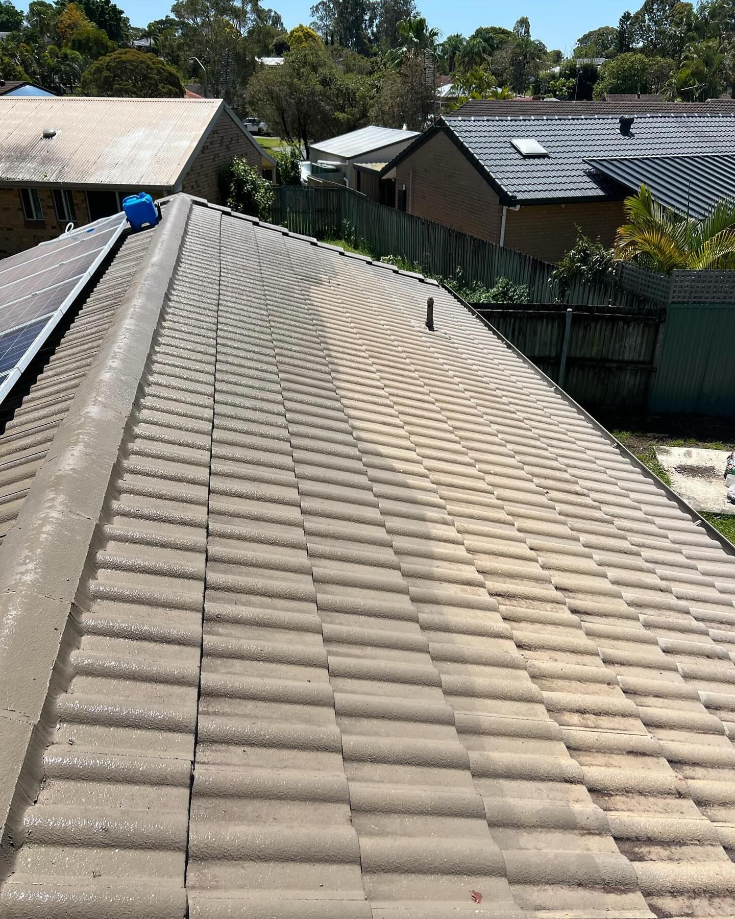 View of a Tan-tiled Roof With Solar Panels. Buildings, and Trees — SEQ Roofing & Painting in Hope Island, QLD