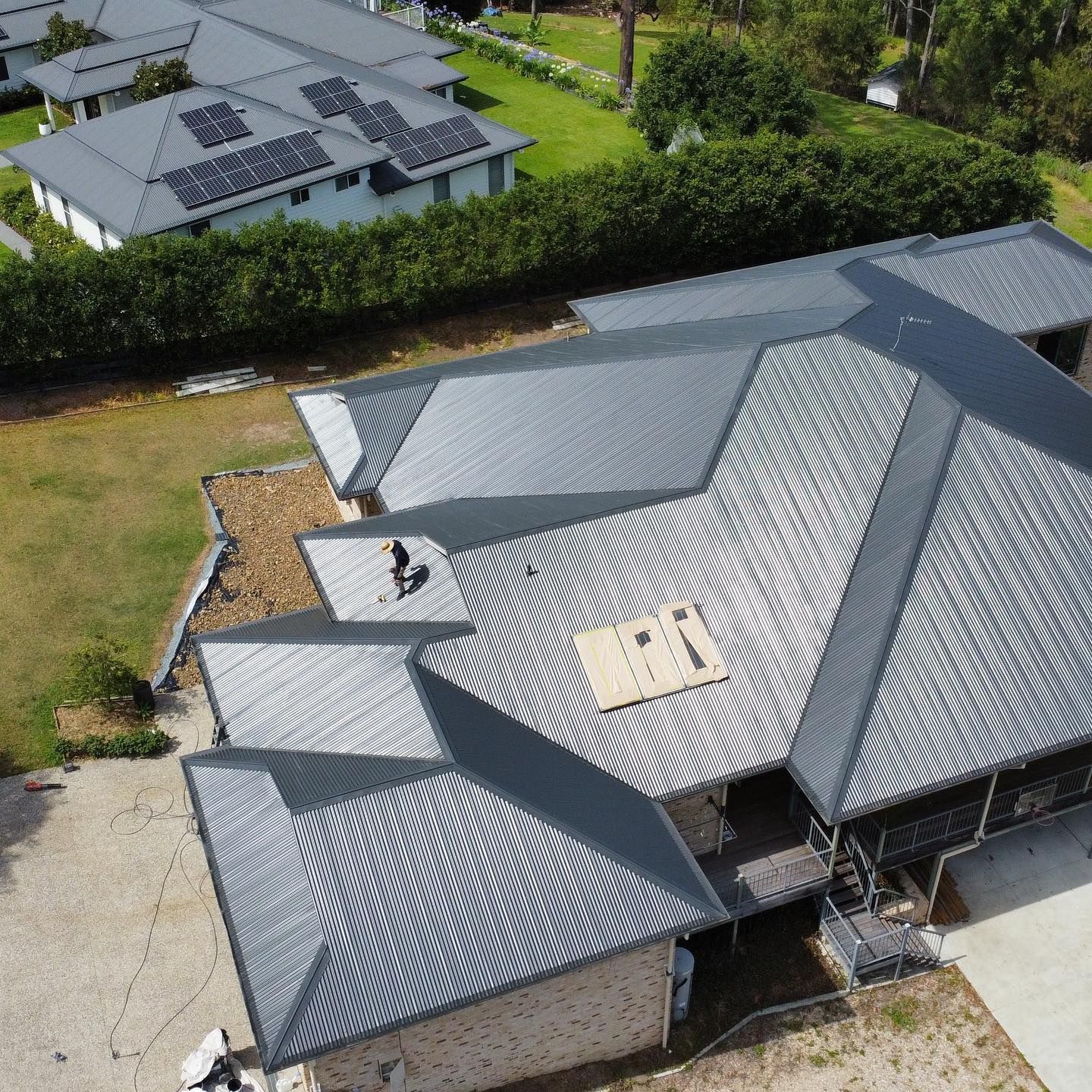 Gray Metal Roof on a House, Angled View, Another House With Solar Panels — SEQ Roofing & Painting in Nerang, QLD
