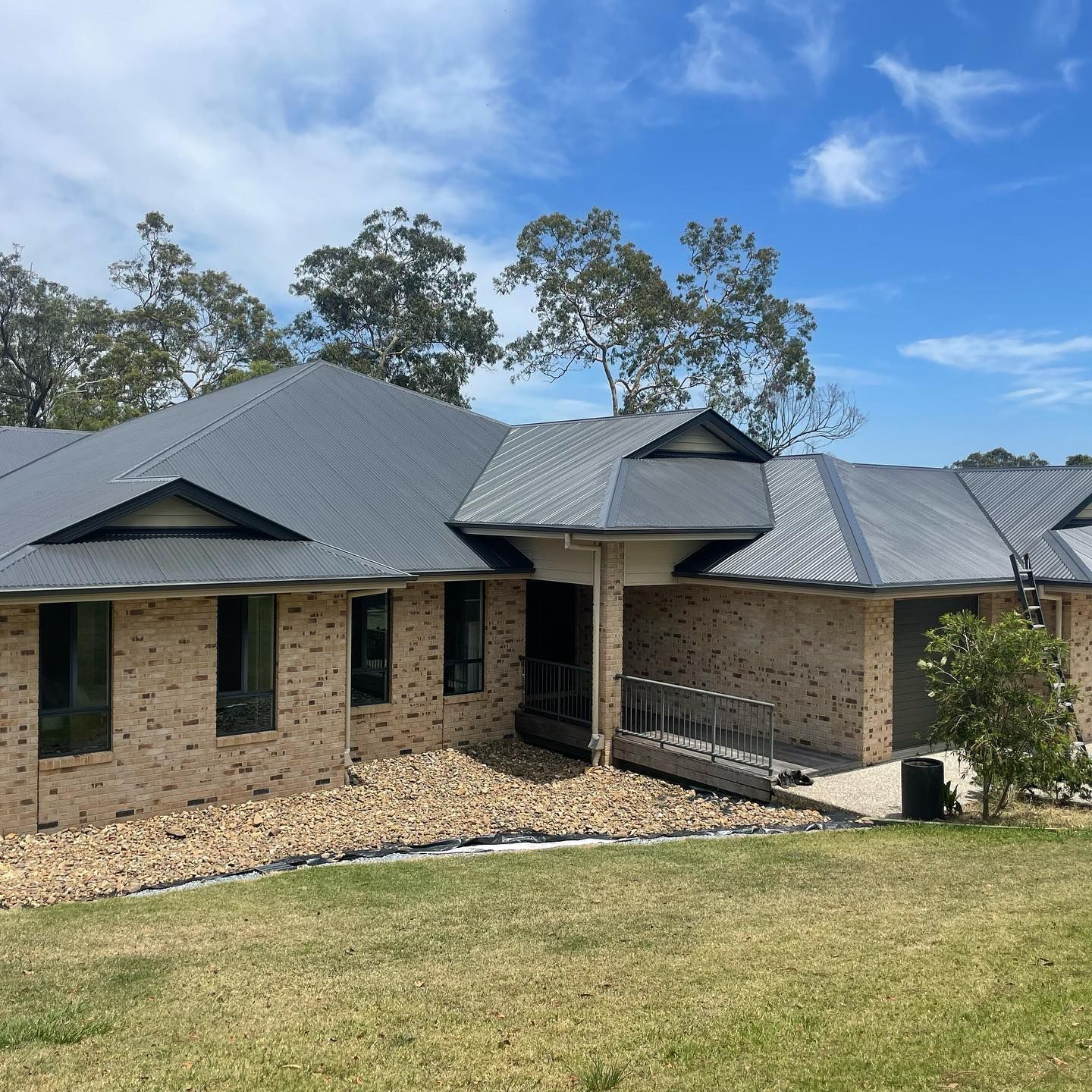 Brick House With a Dark Gray Roof on a Sunny Day — SEQ Roofing & Painting in Nerang, QLD