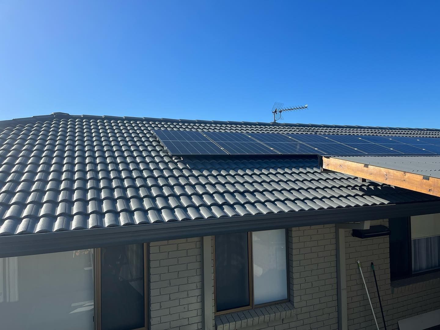 Solar Panels on A Gray Tiled Roof of A Brick Building — SEQ Roof Repaints In Jimboomba, QLD