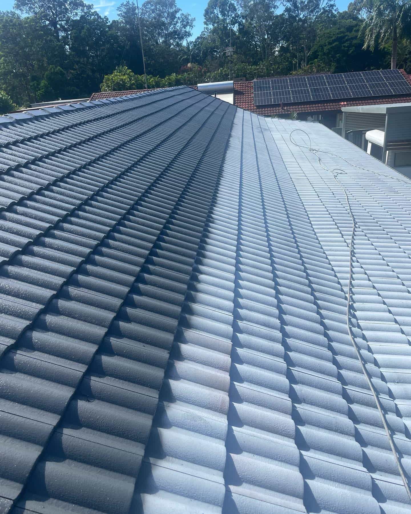 Half of a tiled roof is dark gray and cleaned lighter gray. — SEQ Roof Repaints In Nerang, QLD