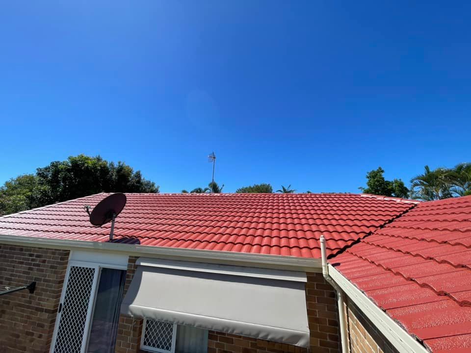 Red Tiled Roof Under a Bright Blue Sky, With a Satellite Dish and Antenna — SEQ Roofing & Painting in Coolangatta, QLD