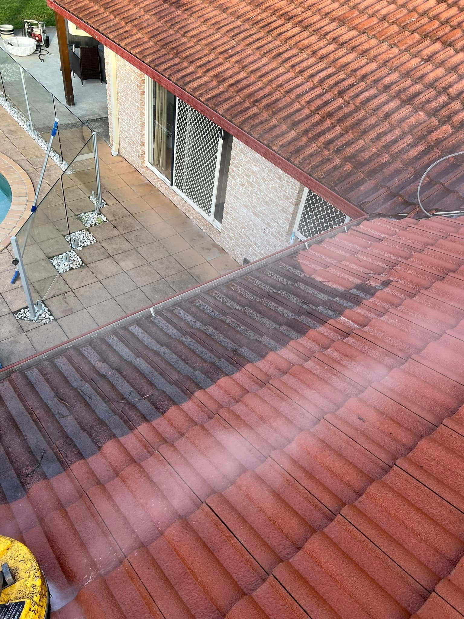 A person pressure washing a red tiled roof, with a patio and pool visible nearby. — SEQ Roofing & Painting in Isle of Capri, QLD