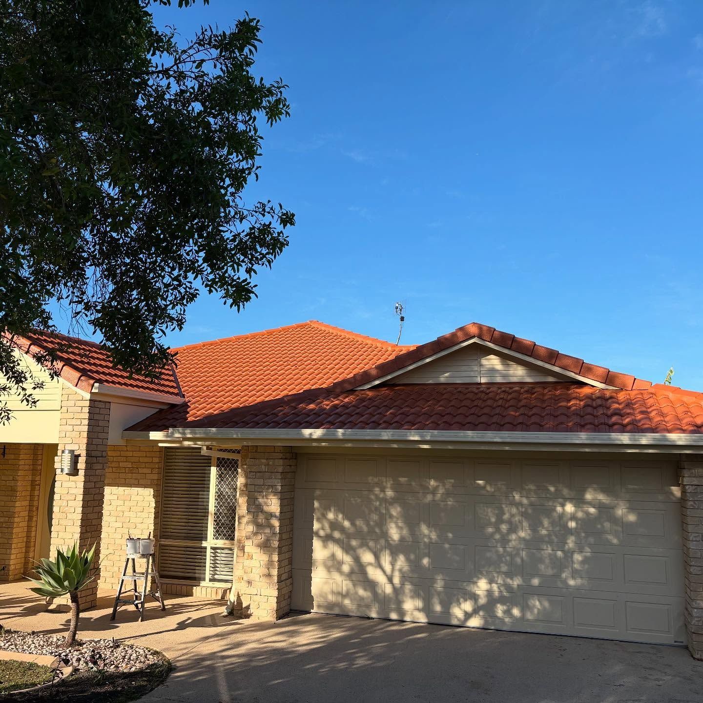 House With Tiled Roof, Beige Exterior, and Closed Garage Door Under a Blue Sky — SEQ Roofing & Painting in Nerang, QLD