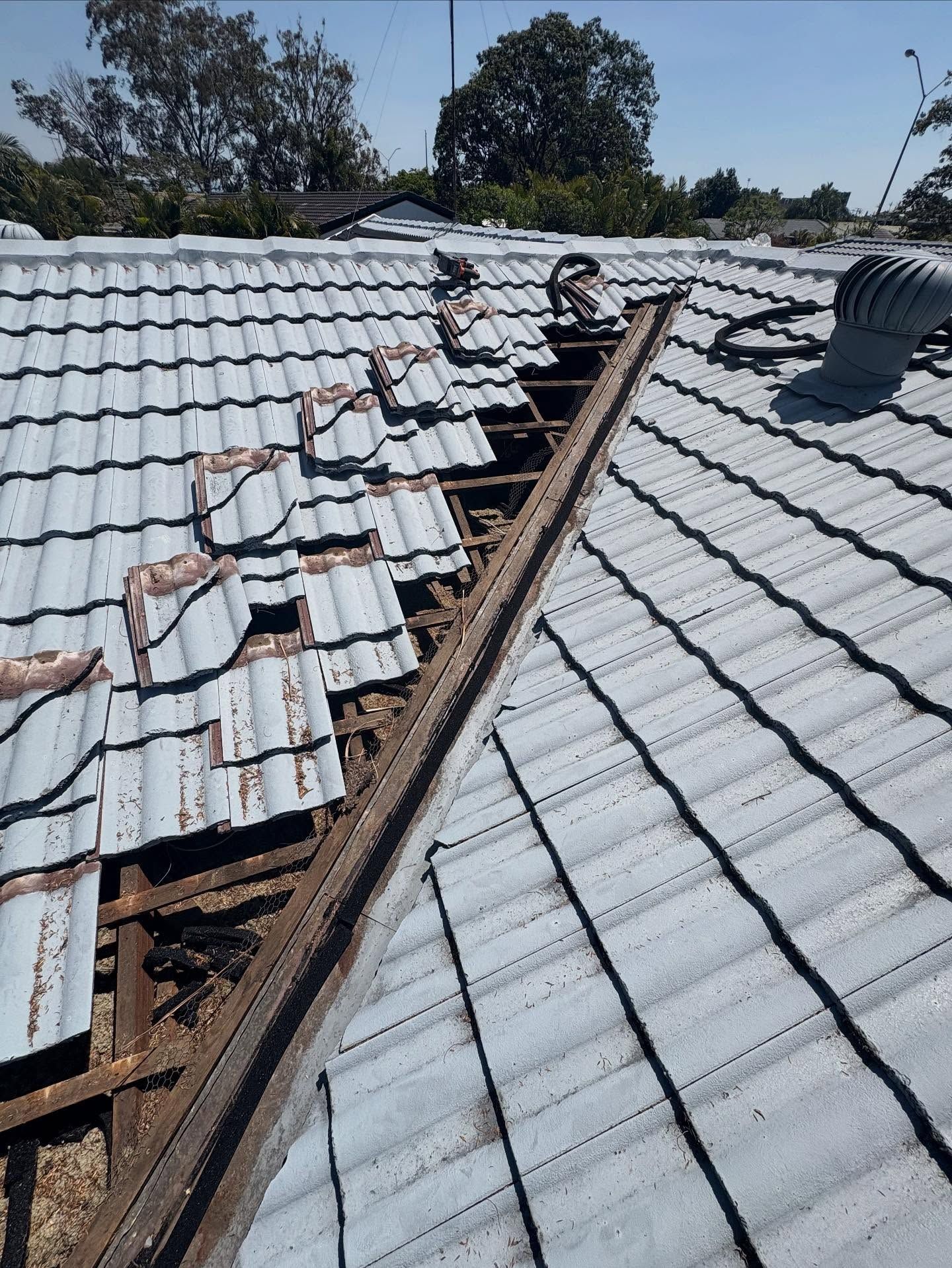 Damaged Roof With Missing Tiles, Revealing Wooden Beams and Debris — SEQ Roofing & Painting in Pacific Pines, QLD
