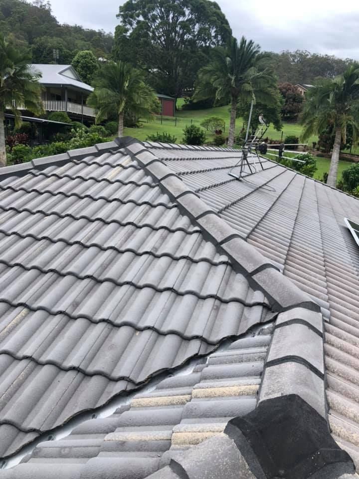 Gray Tiled Roof With Ridge Caps, Set Against a Background of Trees and Houses — SEQ Roofing & Painting in Coolangatta, QLD