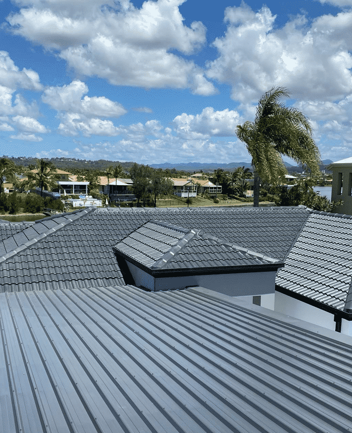 Gray Metal Roof with A Scenic View of Homes Under a Cloudy Blue Sky  — SEQ Roof Repaints In Bonogin, QLD