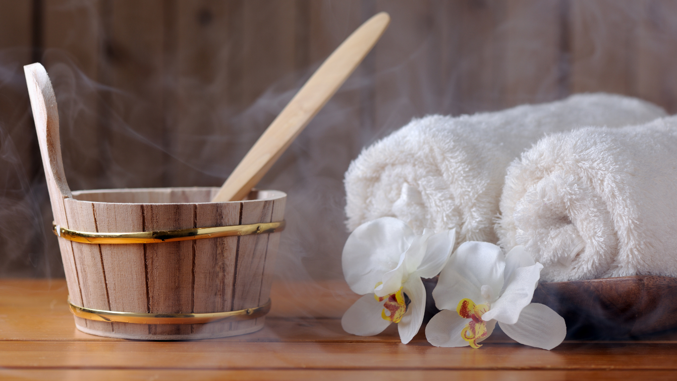 A wooden bucket with a wooden spoon and towels on a wooden table.