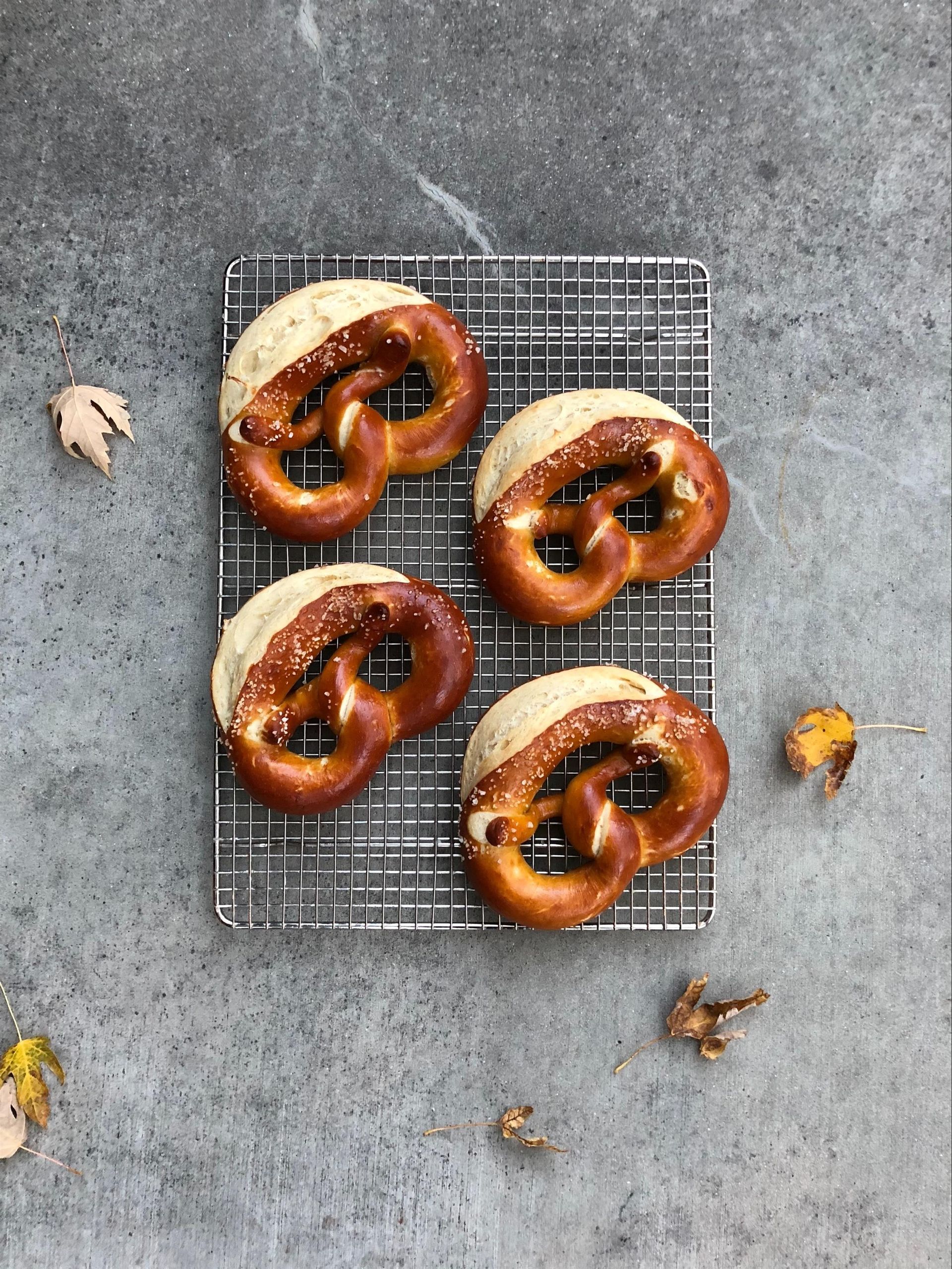 Four pretzel sandwiches are sitting on a cooling rack.