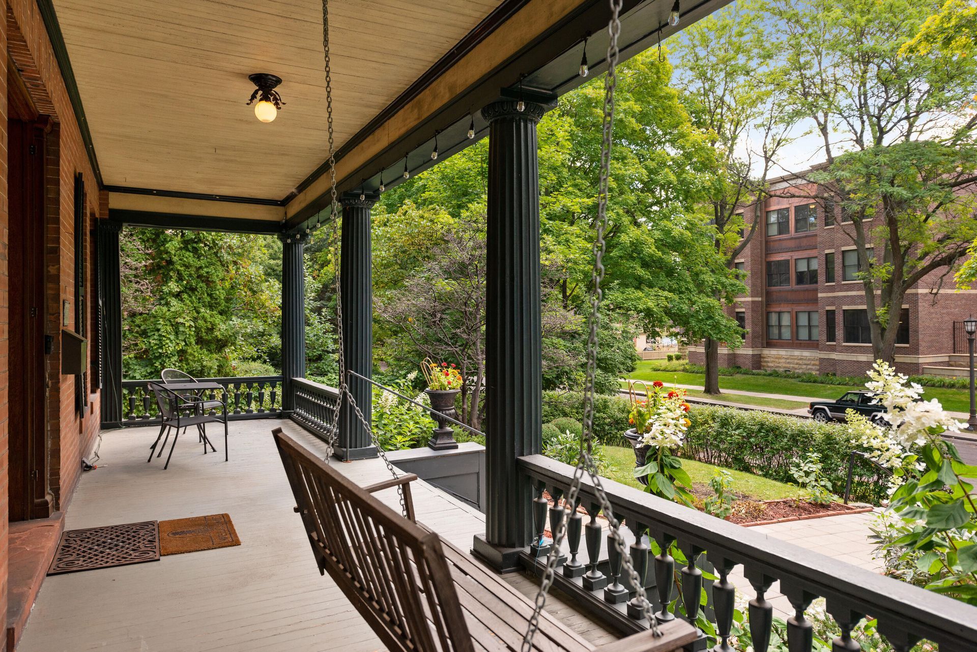 There is a porch with a swing and a table on it.