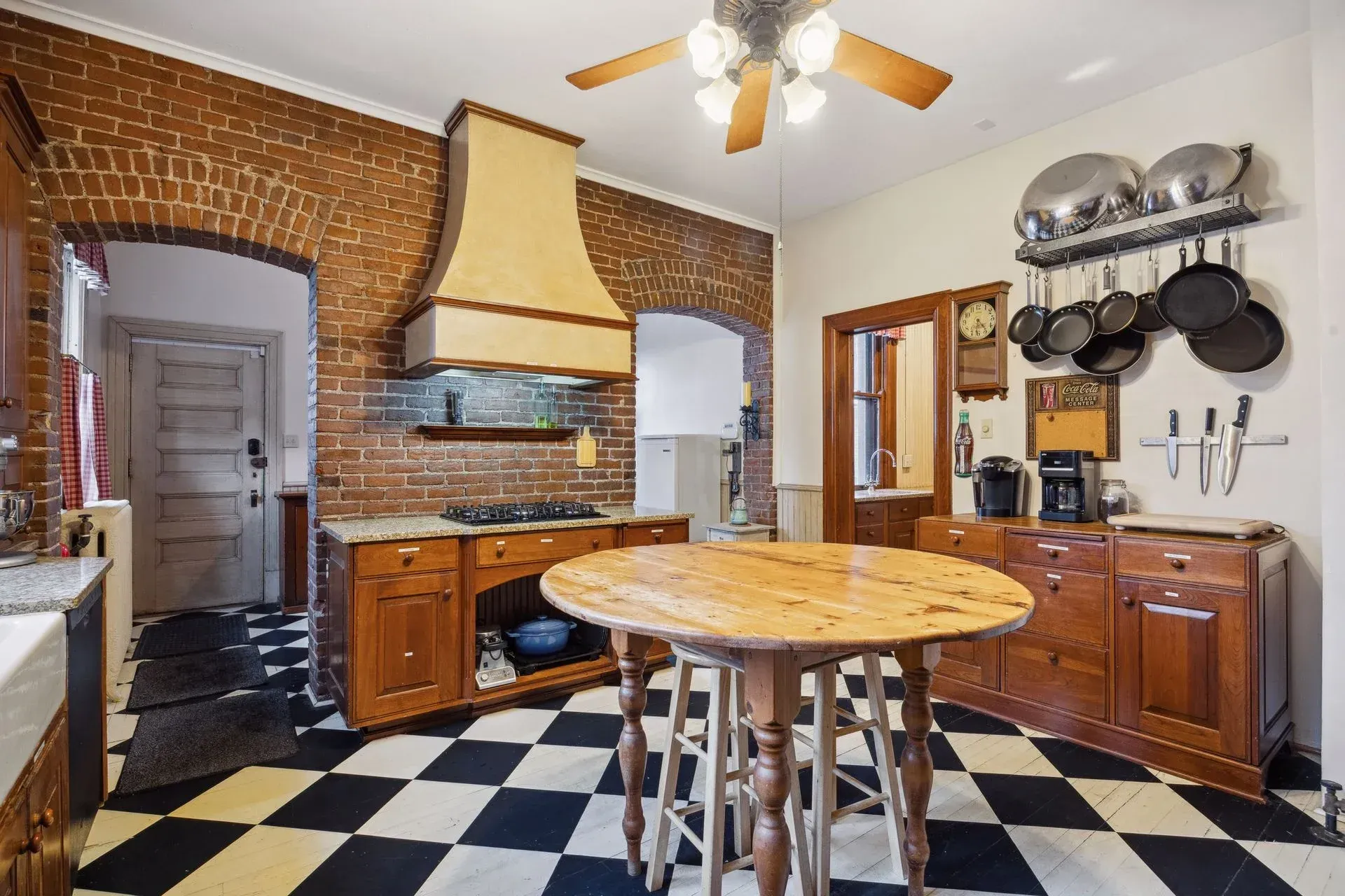 A kitchen with a checkered floor and a wooden table.
