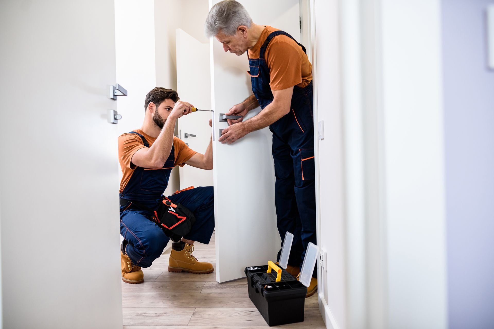 Two Men Are Working on a Door in a Hallway