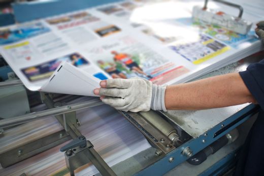 Una persona tiene in mano un pezzo di carta sopra una macchina da stampa.
