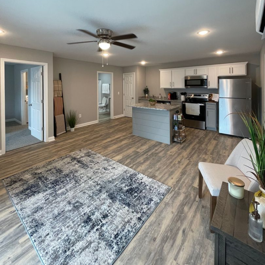 Bedroom with white bedding, brown pillows and throw, and a window with a view.
