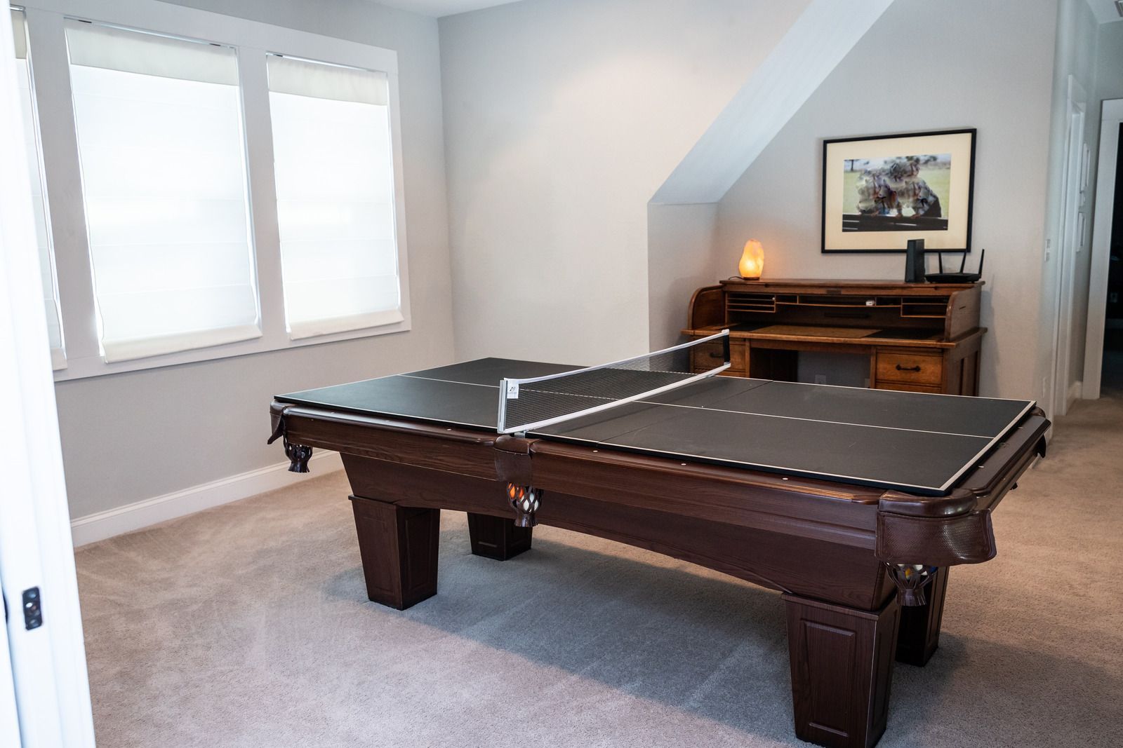 Ping pong table in a room, with a desk and window in the background.