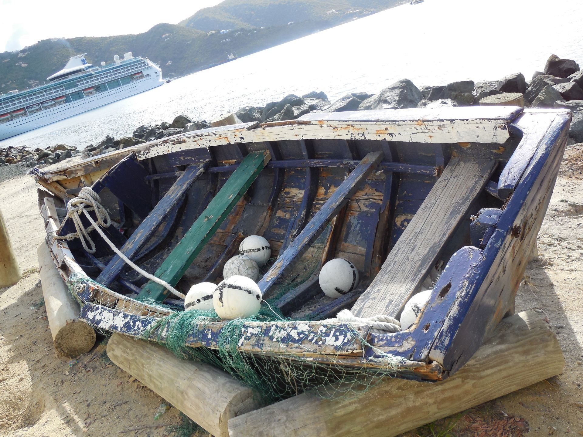 There is a palm tree on the beach with the sun shining through the clouds.