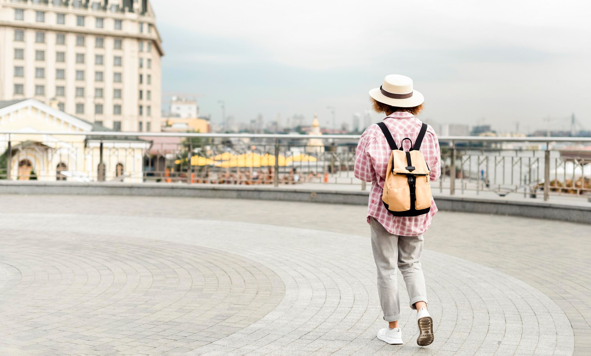 A woman with a backpack is walking across a bridge.