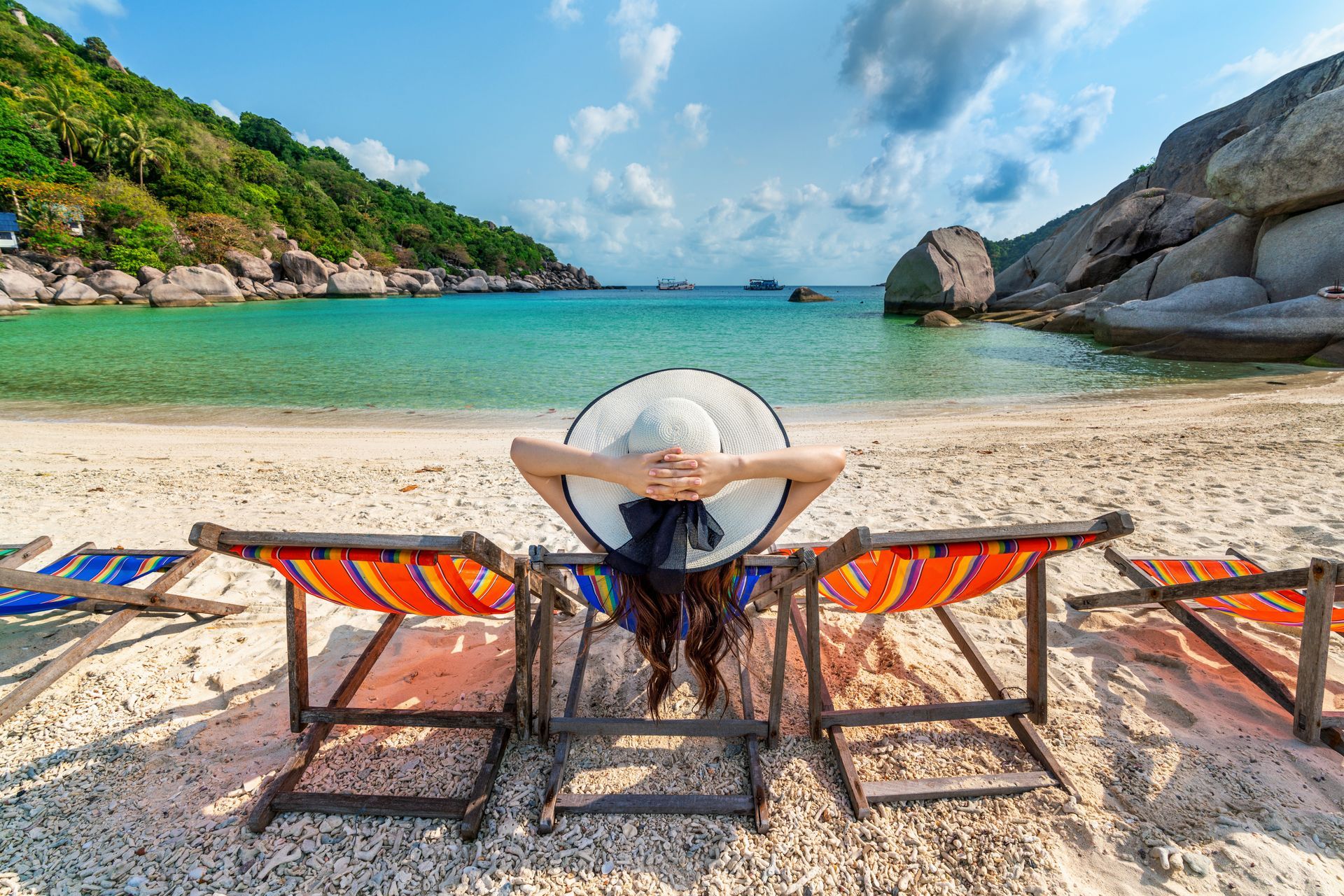 A woman is sitting in a beach chair on the beach.