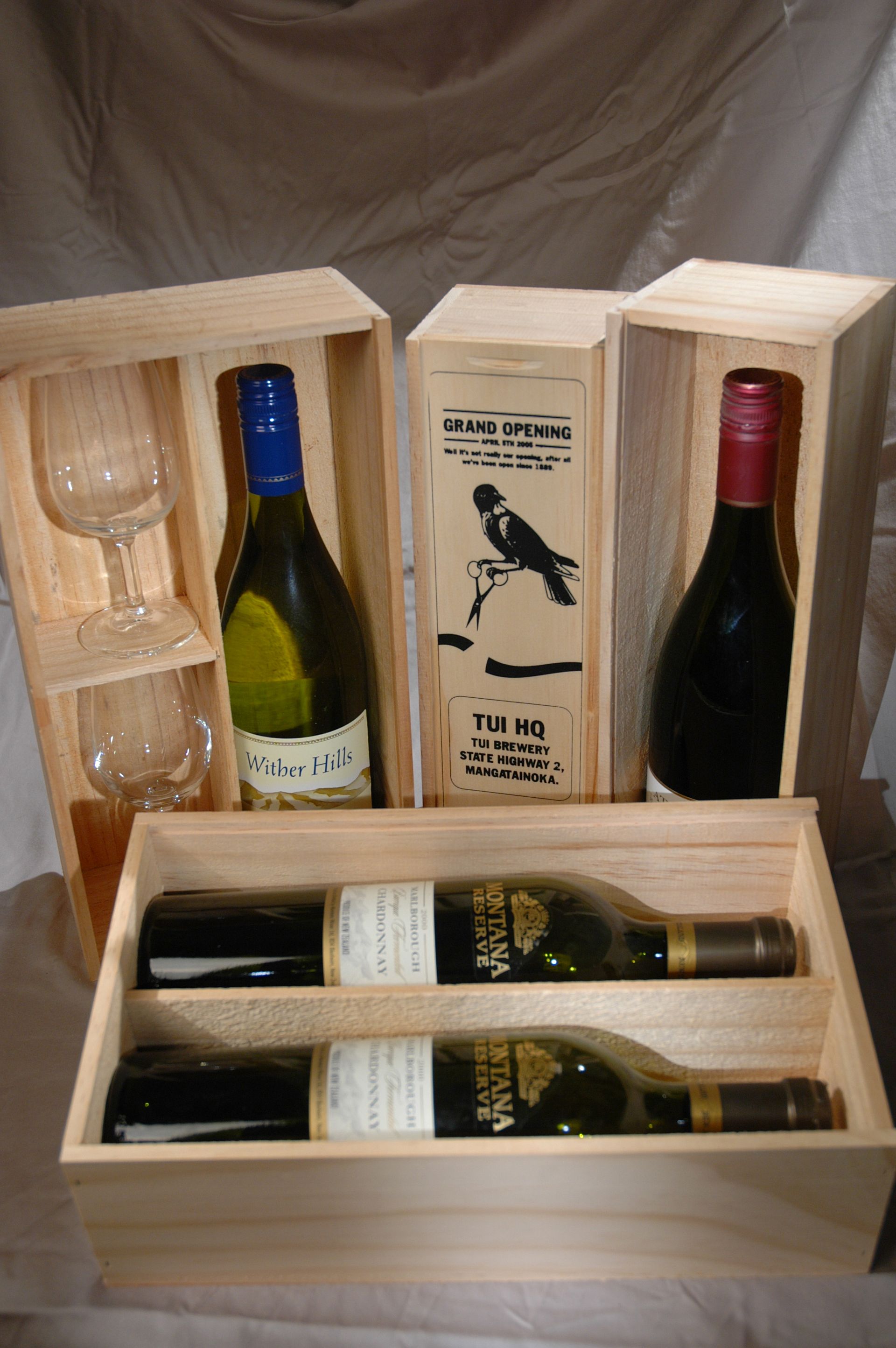 A bottle of wine is in a cardboard box on a wooden table.