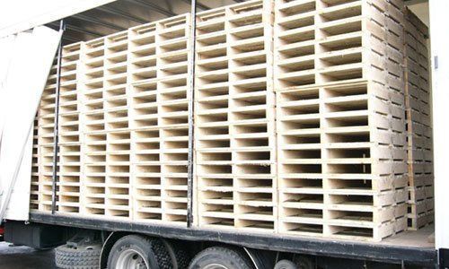 A stack of wooden pallets sitting on top of each other on the ground.